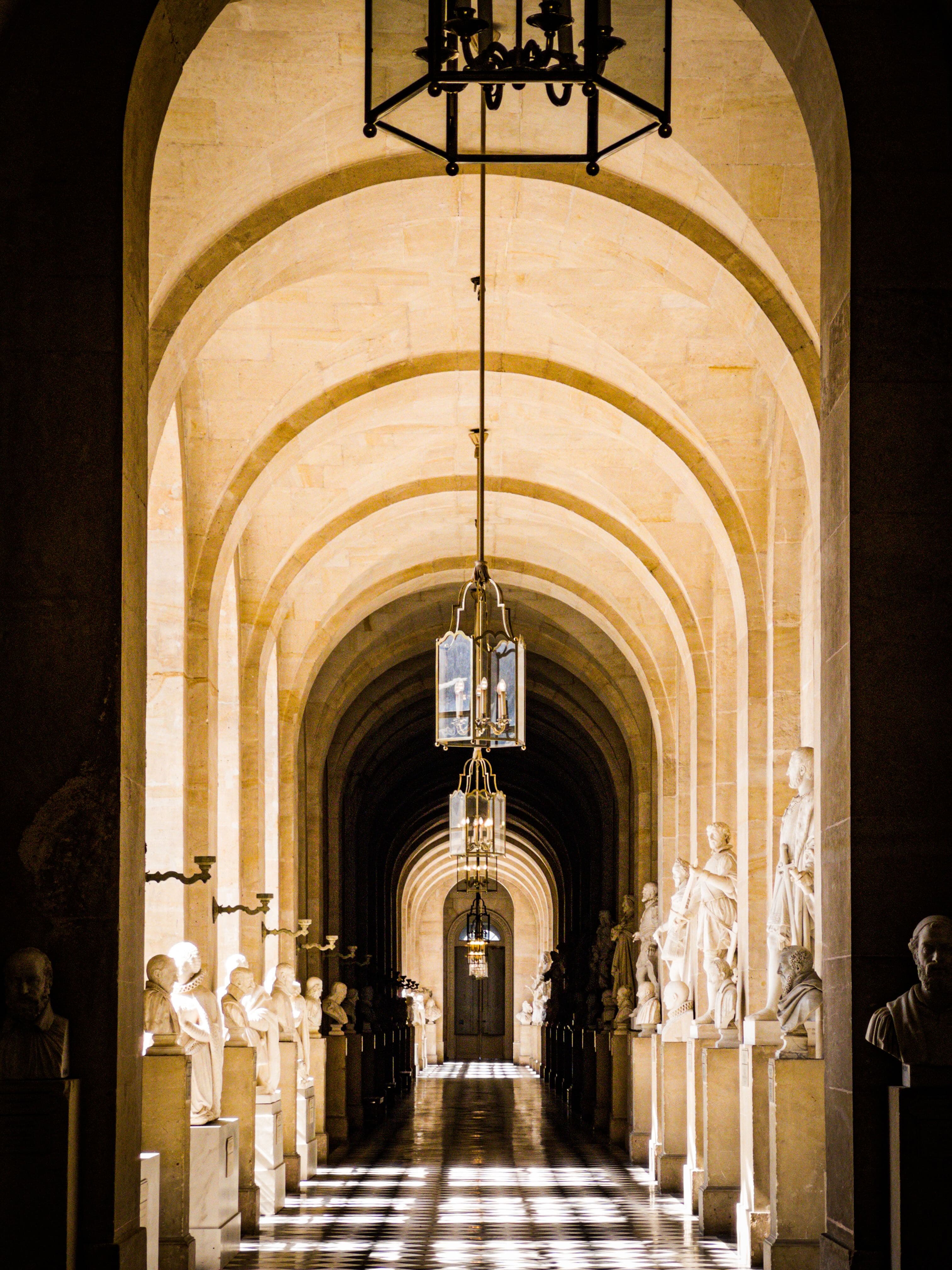 Arched palace corridor lined with statues and lanterns
